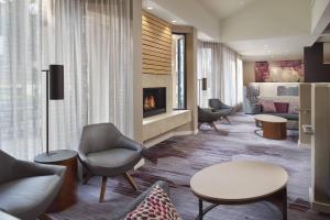 a waiting room with chairs and a fireplace at Courtyard Charlotte Arrowood in Charlotte