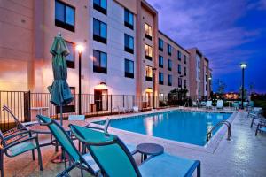 a pool in a hotel with chairs and a umbrella at SpringHill Suites by Marriott Baton Rouge North / Airport in Baton Rouge