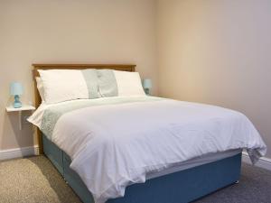 a bedroom with a large bed with white sheets and pillows at Carpenters Cottage in Upwey