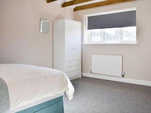 a bedroom with a bed and a dresser and a window at Carpenters Cottage in Upwey