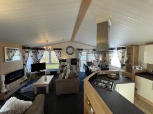 Rudd lake Luxury lakeside lodge with fishing & hot tub@Tattershall في تاتيرشال: غرفة معيشة كبيرة مع مطبخ وغرفة معيشة