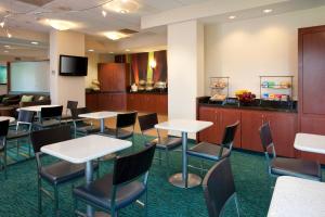 a waiting room with tables and chairs and a tv at SpringHill Suites Los Angeles LAX/Manhattan Beach in Hawthorne