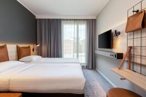 a hotel room with two beds and a tv at Moxy Dortmund City in Dortmund