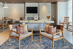 a living room with two chairs and a kitchen at Fairfield by Marriott San Jose Airport Alajuela in Alajuela City