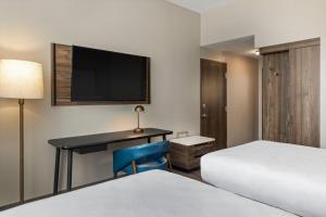a hotel room with two beds and a desk with a television at Fairfield by Marriott San Jose Airport Alajuela in Alajuela City