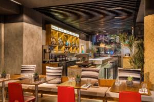 メキシコシティにあるエンバシー スイーツ ホテル バイ ヒルトン メヒコ シティ レフォルマのテーブルと椅子のあるレストラン、バー