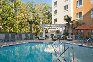 uma piscina num hotel com cadeiras e mesas e um edifício em TownePlace Suites by Marriott Charleston Airport/Convention Center em Charleston