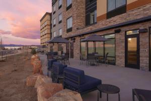 un patio con sedie, tavoli e ombrelloni di fronte a un edificio di Fairfield Inn & Suites by Marriott Fort Collins South a Fort Collins
