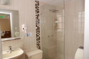 un bagno con doccia, WC e lavandino di Hotel Carolina Montecarlo a Quito