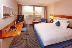 um quarto de hotel com uma cama, uma secretária e uma televisão em Mövenpick Hotel & Casino Geneva em Genebra