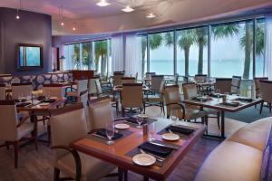 uma sala de jantar com mesas, cadeiras e janelas em Clearwater Beach Marriott Suites on Sand Key em Clearwater Beach