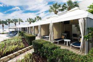 una fila di capanne con sedie, tavoli e palme di Clearwater Beach Marriott Suites on Sand Key a Clearwater Beach