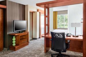a hotel room with a desk with a television and a chair at SpringHill Suites Long Island Brookhaven in Bellport