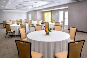 a large room with tables and chairs with flowers on it at SpringHill Suites Long Island Brookhaven in Bellport