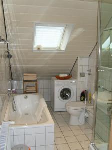 ein Badezimmer mit einer Badewanne, einem WC und einer Waschmaschine in der Unterkunft Ferienwohnung Leichlingen in Leichlingen