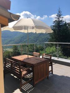 uma mesa de madeira com um guarda-chuva numa varanda em Mansarda / Loft open space em Signora