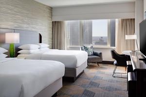 ダラスにあるシェラトン ダラス ホテルのベッド2台とデスクが備わるホテルルームです。