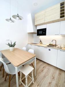 a kitchen with a wooden table and white cabinets at Beach & Castle - Sines Apartment in Sines