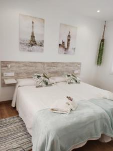 two beds in a white room with pictures on the wall at Gallaecia in Arzúa