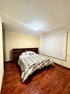 1 dormitorio con 1 cama y suelo de madera en Departamento de Patricia, en Sucre