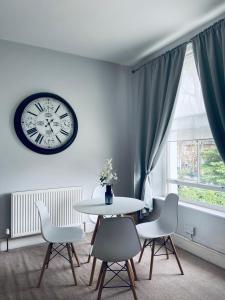 comedor con mesa, sillas y reloj en London Oval Apartment, en Londres