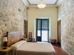 1 dormitorio con cama y pared de piedra en Casa Cundaro en Girona