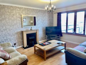 sala de estar con chimenea y TV en The Wee Gem - 9 Milking Hill Park en Stornoway