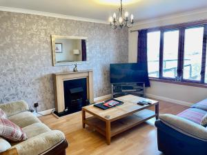 a living room with a fireplace and a tv at The Wee Gem - 9 Milking Hill Park in Stornoway