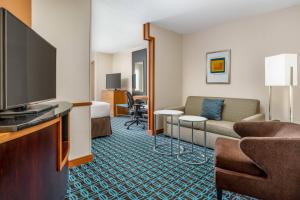 a hotel room with a couch and a flat screen tv at Fairfield by Marriott Peoria East in Peoria