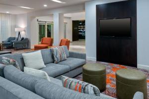 a living room with a couch and a flat screen tv at Courtyard by Marriott Sarasota at University Town Center in Sarasota