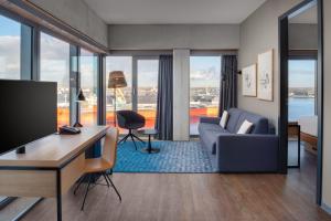 een woonkamer met een bank en een bureau met een televisie bij Residence Inn by Marriott Amsterdam Houthavens in Amsterdam