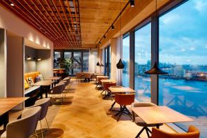 un restaurante con mesas, sillas y ventanas grandes en Residence Inn by Marriott Amsterdam Houthavens en Ámsterdam