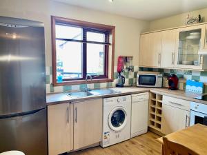 a kitchen with a stainless steel refrigerator and a dishwasher at The Wee Gem - 9 Milking Hill Park in Stornoway