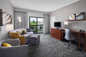 コラオポリスにあるCourtyard by Marriott Pittsburgh Airportのソファ、デスク、テレビが備わるホテルルームです。