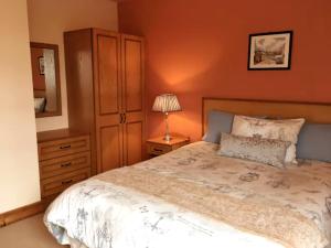 a bedroom with a bed and a dresser and a lamp at The Clady in Bunbeg