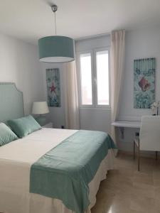 een slaapkamer met een bed, een bureau en ramen bij Coral Oro en la Caleta Ha Apartment in Cádiz