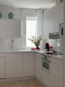 een witte keuken met witte kasten en een raam bij Coral Oro en la Caleta Ha Apartment in Cádiz