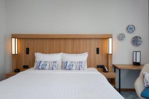 ein Schlafzimmer mit einem großen Bett mit blauen und weißen Kissen in der Unterkunft Courtyard by Marriott Bucharest Floreasca in Bukarest