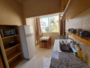 La cuisine est équipée d'un réfrigérateur blanc et d'un évier. dans l'établissement Agreable appartement dans une résidence calme sécurisée, à Harhoura