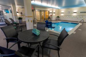 a pool with a table and chairs next to a swimming pool at Fairfield Inn & Suites by Marriott Geneva Finger Lakes in Geneva