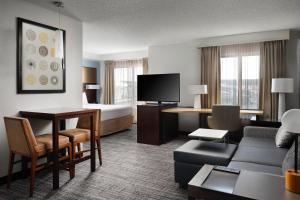a hotel room with a bed and a living room at Residence Inn by Marriott Grand Rapids Airport in Grand Rapids