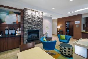 a living room with a fireplace and blue chairs at Fairfield Inn and Suites by Marriott Nashville Smyrna in Smyrna