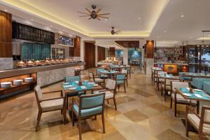 um restaurante com mesas e cadeiras e um bar em Goa Marriott Resort & Spa em Panaji