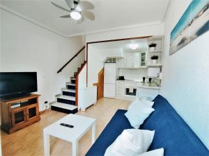 sala de estar con sofá azul y TV en Bonita casa al lado de la playa en Santa Pola, en Santa Pola