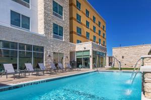 a swimming pool with chairs and a building at Fairfield Inn & Suites Houston Memorial City Area in Houston