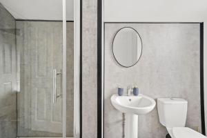 uma casa de banho com um WC, um lavatório e um espelho. em Platinum Grove Modern Flat em Kent