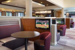 a waiting room with a tv and a table and chairs at Courtyard by Marriott Raleigh Cary in Cary