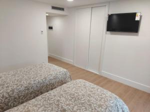 a room with two beds and a flat screen tv at Hotel - Hostel Atuvera in Santo Domingo de la Calzada