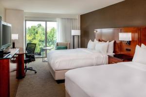 Habitación de hotel con 2 camas, escritorio y TV. en Delta Hotels by Marriott Chesapeake Norfolk, en Chesapeake