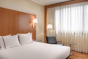 sypialnia z dużym białym łóżkiem i krzesłem w obiekcie AC Hotel Genova by Marriott w Genui